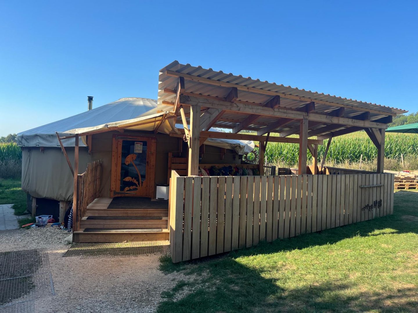 Holzhütte mit überdachter Terrasse neben einem Feld