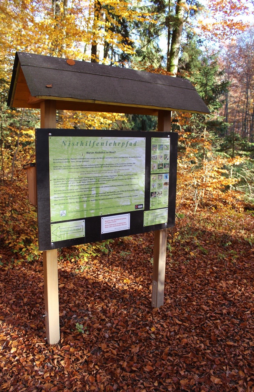 Infotafel „Nisthilfenlehrpfad“ im herbstlichen Wald