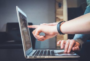 Zwei Hände zeigen auf einen Laptop